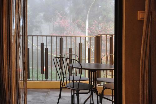 a balcony with a table and chairs in front of a window at Sheng Shine Forest Resort in Lugu Lake