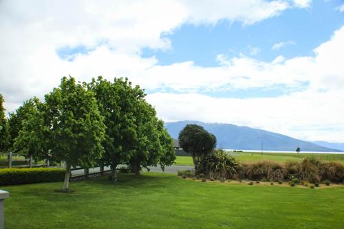 a green park with trees and mountains in the background at Dunluce Boutique B&B in Te Anau
