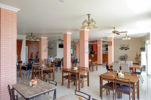 uma sala de jantar com mesas e cadeiras de madeira em RedDoorz Plus Syariah @ Hotel Boulevard Luwuk em Luwuk