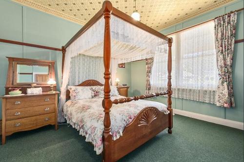una camera con letto a baldacchino in legno e cassettiera di Comstock Cottage Welcomes You a Queenstown