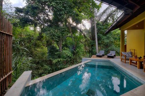 a swimming pool with two chairs and a house at Samkhya Villas - CHSE Certified in Ubud