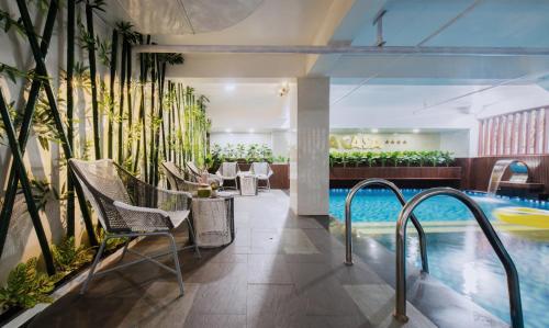 un vestíbulo de hotel con piscina, sillas y plantas en La Casa Hotel Nha Trang, en Nha Trang