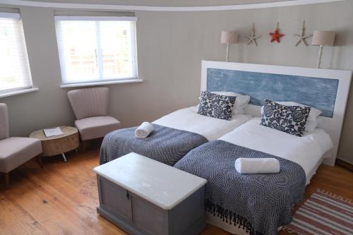 a bedroom with two beds and a couch and a chair at Amber Light Wilderness Beach Cottage in Wilderness