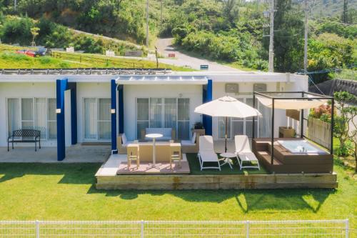 a house with a patio with chairs and an umbrella at Hermit Hills Okinawa  -SEVEN Hotels and Resorts- in Onna