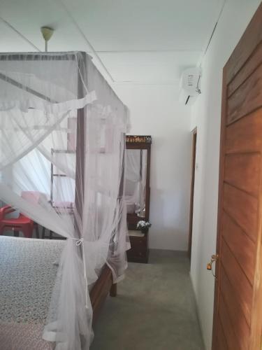 a bedroom with a bed with a mosquito net at Lasindu Guest in Ahangama