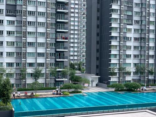a large swimming pool in front of tall buildings at Relaxed Family Staycation, Pool View w WIFI n Netflix in Bangi