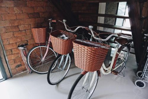 two bikes with baskets are parked next to a brick wall at Tha Ma-O Bouteak homestay - ท่ามะโอบูทีคโฮมสเตย์ - pet friendly in Lampang