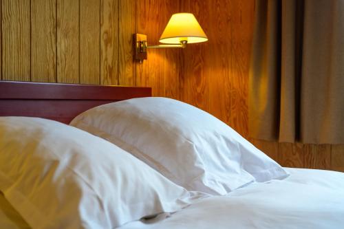 an unmade bed with white sheets and a lamp at Domaine Du Val in Grand-Laviers