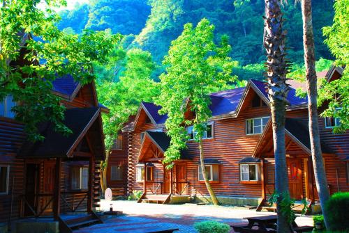 a log cabin with trees and mountains in the background at Master Bear Resort in Jiafeng