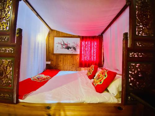 a small bedroom with a canopy bed with red pillows at Xishan Wutong Qinyuan (Free Pick up Service) in Huangshan