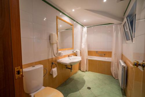 a bathroom with a toilet and a sink and a tub at Family Park Hotel Kyoshkove in Shumen