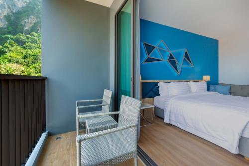 a bedroom with a bed and a blue wall at BlueSotel SMART Krabi Aonang Beach - Adults only in Ao Nang Beach