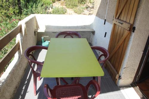 uma mesa verde e cadeiras numa varanda em Suarella em Propriano
