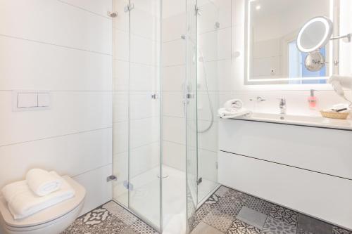 a bathroom with a shower and a toilet and a sink at Hotel Vier Jahreszeiten Binz in Binz