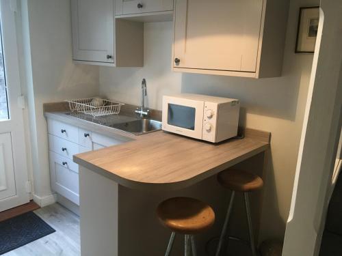 a kitchen with a microwave on a counter with stools at Self-Contained Accommodation for 2 in Keswick