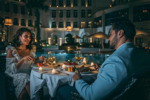a man and a woman sitting at a table with a meal at Royal Maxim Palace Kempinski Cairo in Cairo