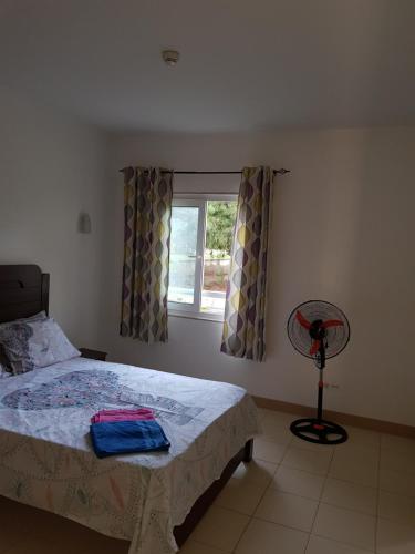a bedroom with a bed and a window and a fan at Surf Beach Vila Verde apartments in Santa Maria
