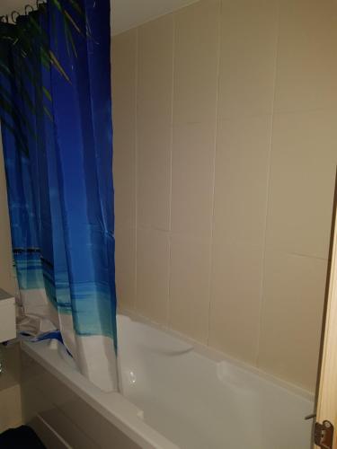 a bathroom with a shower with a blue shower curtain at Surf Beach Vila Verde apartments in Santa Maria