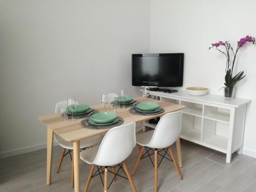 a dining room table with white chairs and a television at Casa da Levada in Ribeira Grande