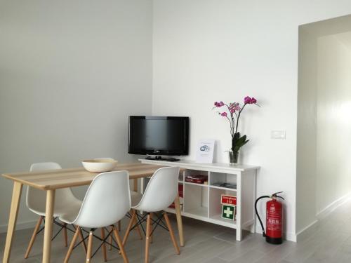 a dining room table with white chairs and a television at Casa da Levada in Ribeira Grande