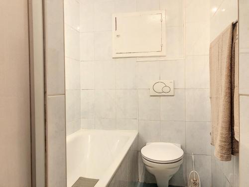 a white bathroom with a toilet and a bath tub at Apartment Del Sol Sion Center in Sion