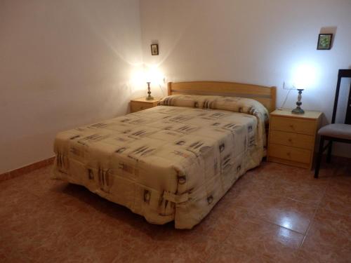a bedroom with a bed and two tables and a chair at Apartamento funcional y acogedor in L'Ametlla de Mar