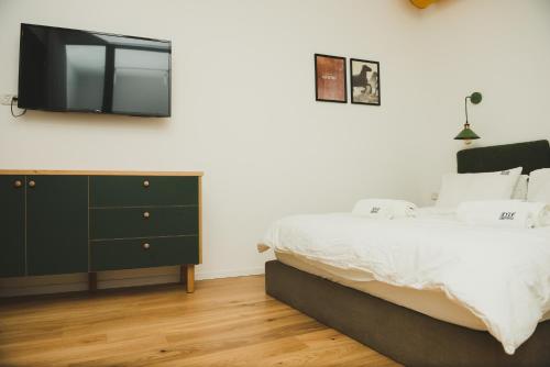 a bedroom with a bed and a tv on the wall at The Rambam Residence - By Localz Group in Tel Aviv