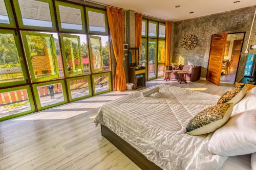 a bedroom with a bed in a room with large windows at Tonmai Suites in Ko Lanta