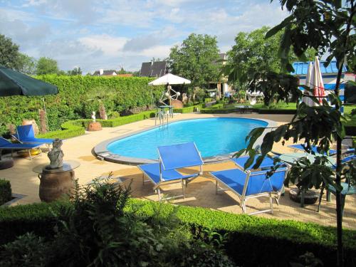 a swimming pool with blue chairs and an umbrella at B&B Casa Roman & Vakantiewoning voor 1 pers tot max 32 personen in Zonhoven
