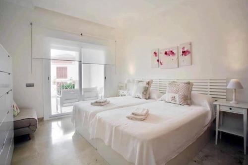 Un dormitorio blanco con una cama grande y una ventana en Apartamento familiar con JARDIN y TERRAZA Privada, en Alcaidesa