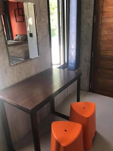 a wooden table with two orange stools in a room at Janrawee Resort in Ban Phang Kan Nua