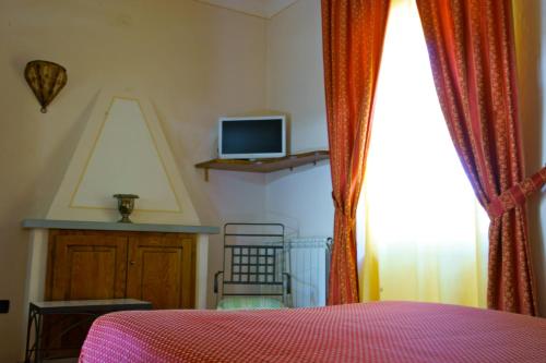 a bedroom with a bed and a tv and a window at Locanda Ristorante Gavarini in Bagnone