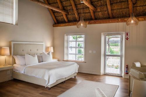 a bedroom with a white bed and two windows at Rijk's Wine Estate & Hotel in Tulbagh