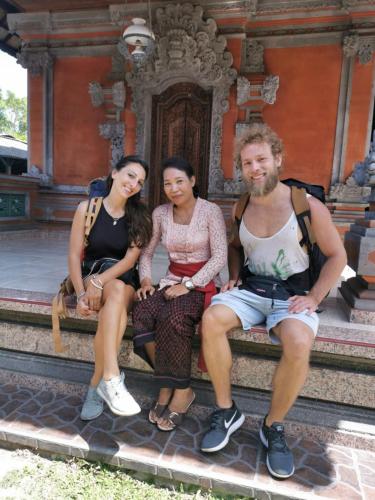three people sitting on a bench in front of a building at Jero Ratna Homestay in Ubud