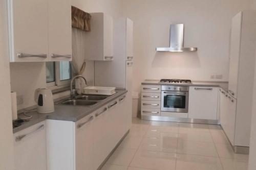 eine weiße Küche mit einer Spüle und einem Herd in der Unterkunft Luxurious Furnished apartment in sliema in Sliema