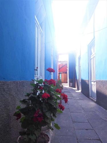 a blue building with red flowers and an umbrella at Casona Moya in Arequipa