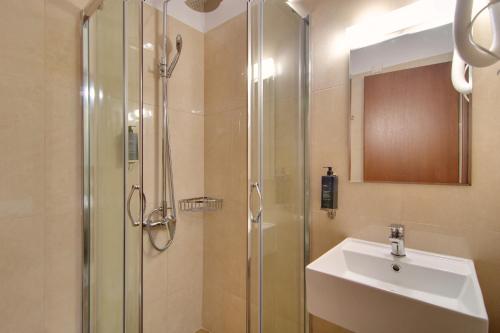 ein Bad mit einer Dusche, einem Waschbecken und einem Waschbecken in der Unterkunft Ali Pasha Hotel in Ioannina