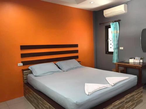 a bedroom with a large bed with an orange wall at Janrawee Resort in Ban Phang Kan Nua