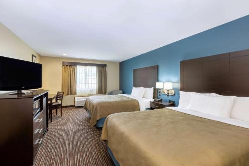 a hotel room with two beds and a flat screen tv at AmericInn by Wyndham Jefferson in Jefferson