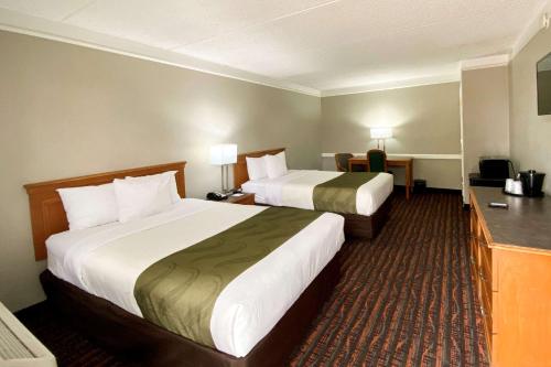 a hotel room with two beds and a desk at Quality Inn Harlingen in Harlingen