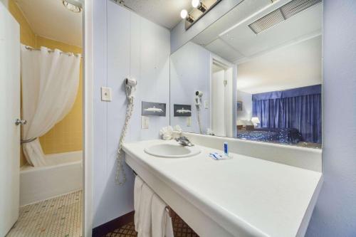 La salle de bains est pourvue d'un lavabo, d'un miroir et d'une baignoire. dans l'établissement Hospitality Inn, à North Platte