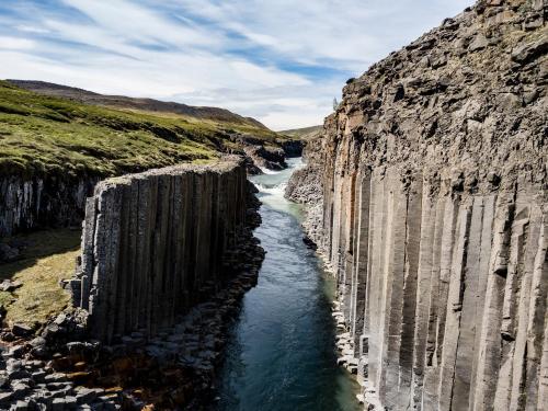 a river cutting through a rocky cliff at Studlagil Canyon country home - Hotel Studlagil Canyon in Grund
