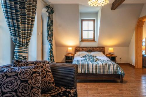 a bedroom with a bed and a chair and a window at Butorowy Dwór in Kościelisko
