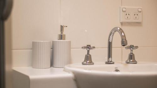 un lavabo con 2 grifos y un rollo de toallas de papel en Tasha's Apartments on Kerry, en Pennington
