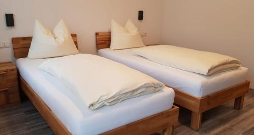 two beds in a room with white sheets and pillows at Gasthaus Pension Hörner in Moos