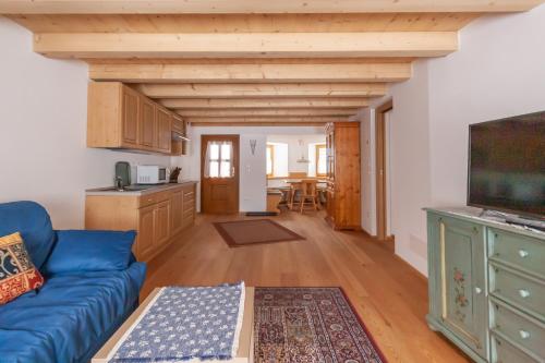 a living room with a blue couch and a kitchen at Casa Piccolin in Falcade