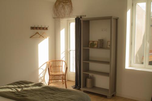 ein Schlafzimmer mit einem Bett, einem Stuhl und einem Fenster in der Unterkunft LA CENTENAIRE GRUISSAN - Maison d'Hôte in Gruissan