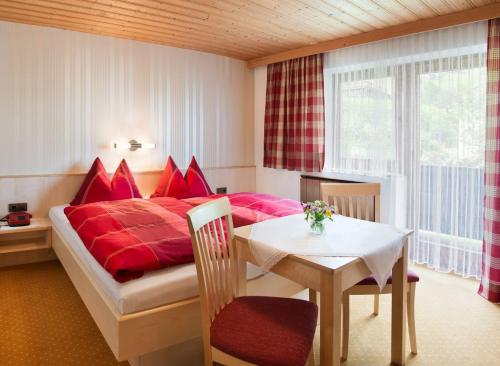 a bedroom with a red bed with a table and a tableablish at Gästehaus Hofer in Brixen im Thale