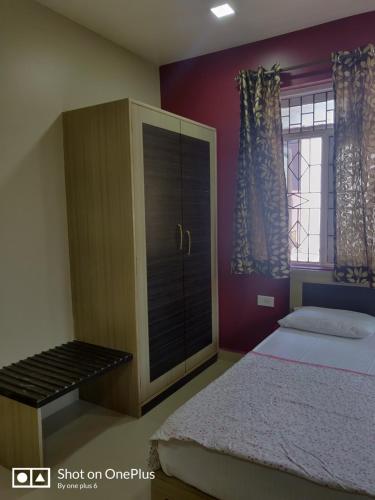 a bedroom with a bed and a cabinet and a window at Guesthouse Sakina Colva in Colva
