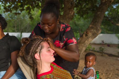 a woman getting her hair cut by a girl at Tamba Kuruba Eco-lodge in Folonko